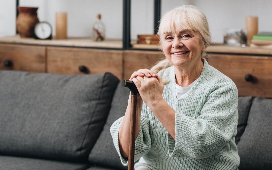 Oudere vrouw met een stok die zit op een bank, last van urge incontinentie