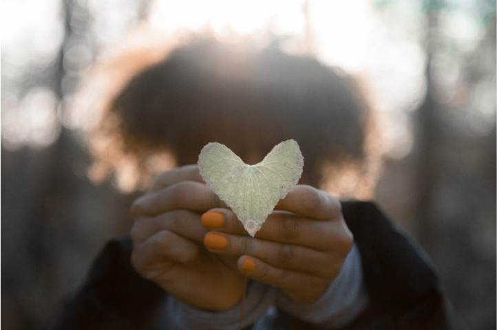 Léontine blij met stop urineverlies nu Blije vrouw toont hartje gemaakt van een herfstblaadje na succesvol stoppen van urineverlies.